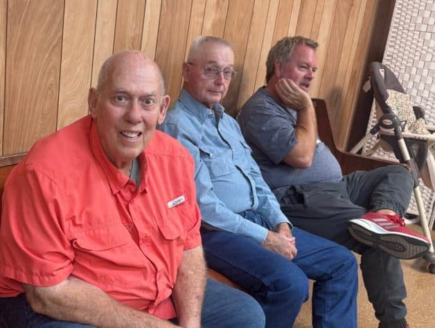 Three men visiting together in the fellowship hall